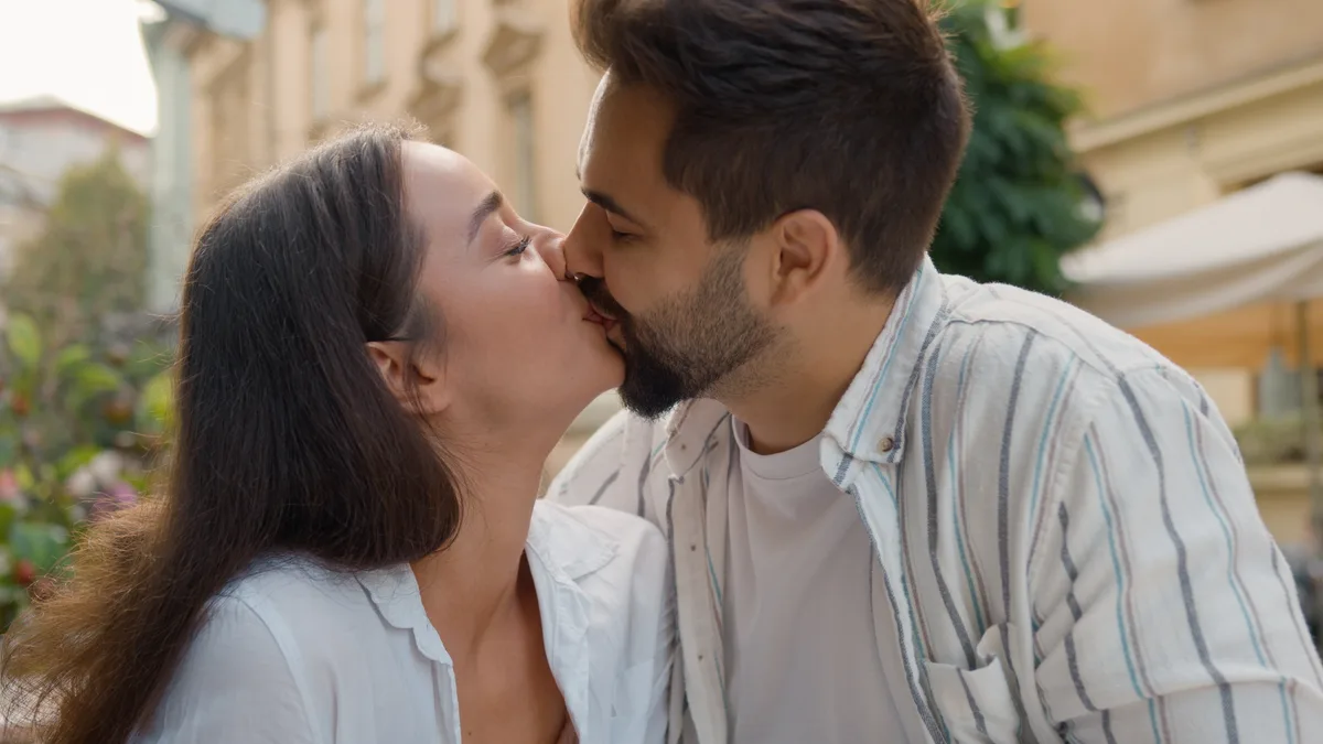 Adult couple kissing outdoors, illustrating young-adult HSV dating and romantic connection